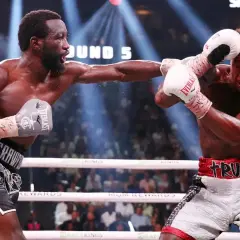 Terence Crawford lands a punch wearing grey Everlast gloves. His opponent, wearing white Everlast gloves, attempts to block.