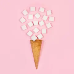 Ein Waffelhörnchen fängt einen Schwall aus Würfelzucker auf. Ein süßer Traum, der wie ein eis zucker aussieht.