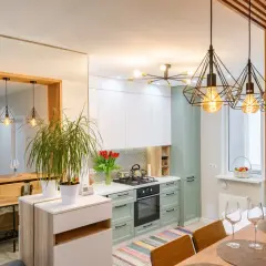Nowoczesna kawalerka z aneksem kuchennym, jadalnią i salonem. Wnętrze rozświetlają geometryczne lampy.
