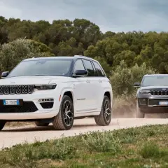 Dwa Jeepy, biały i czarny, jadące po piaszczystej drodze. Jeep kraj pochodzenia to USA, ale te modele wyglądają na europejskie.