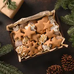Kiste mit selbstgemachten Weihnachtsplätzchen, Sternen und Bäumen, perfekt zum Basteln von Weihnachtsgeschenken. Tannenzweige und Zapfen schmücken die Szene.