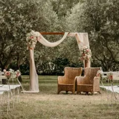 Un décor champêtre pour une célébration laïque : chaises blanches, arche fleurie, fauteuils en rotin sous les oliviers.