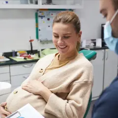 Donna incinta sorride dal dentista, preoccupata per la carie in gravidanza.