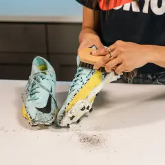 Une personne utilise une brosse pour nettoyer des chaussures de foot sales. Apprenez comment laver chaussures de foot qui puent pour qu'elles retrouvent leur éclat.
