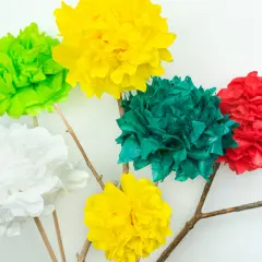 Bunte Seidenblumen basteln: Fünf Papierblumen in Rot, Grün, Gelb und Weiß auf Holzästen vor weißem Hintergrund.