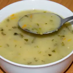 Łyżka zupy ogórkowej z widocznymi kawałkami warzyw. Czy zupa ogórkowa jest lekkostrawna? Tak, ta wygląda na idealną na lekki obiad.