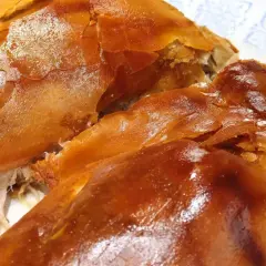 Un crujiente cochinillo al horno, con piel dorada y carne jugosa, listo para ser disfrutado.