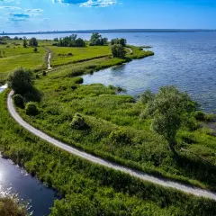 Malownicze trasy rowerowe Szczecin wiodące wzdłuż rzeki i jeziora, otoczone bujną zielenią.