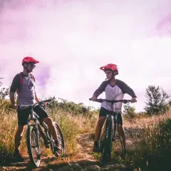 Dwóch rowerzystów w kaskach na tle fioletowego nieba, gotowych do jazdy po malowniczych trasach rowerowych Lublin.