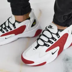 Białe buty Nike z czerwonymi akcentami i czarnymi sznurówkami. Numer "2000" na sznurówkach nawiązuje do historii marki Nike.