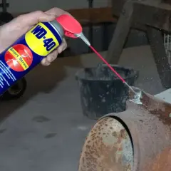 WD-40 wird auf einen verrosteten Kaminofen gesprüht, um Rost zu entfernen.