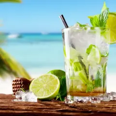 Orzeźwiający mojito przepis na plaży. Szkło z lodem, limonką i miętą, z palmą i morzem w tle.