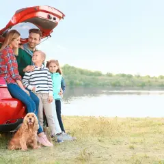 Famille heureuse avec leur chien près d'un lac, profitant d'un voyage dans un pays dog friendly.