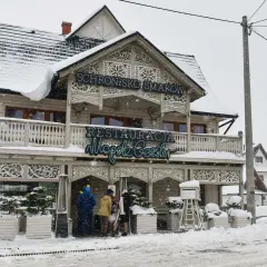 Drewniana restauracja "Schronisko Smaków" w Bukowinie Tatrzańskiej, pokryta śniegiem, z neonem "Restauracja".
