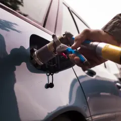 Rifornimento GPL. Se la bombola gpl scaduta posso circolare a benzina? La mano inserisce la pistola di rifornimento nel serbatoio dell'auto.
