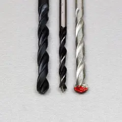 Trois forets de tailles différentes, dont un avec une pointe rouge, prêts à percer un chemin à travers un matériau, comme un foret dans un foret.