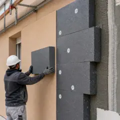 Operaio applica pannelli isolanti su facciata. Un esempio concreto di etics significato: costruire in modo sostenibile per il futuro.
