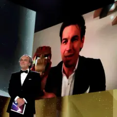Presentador en los Goya con Mario Casas en pantalla, quien sostiene un premio.
