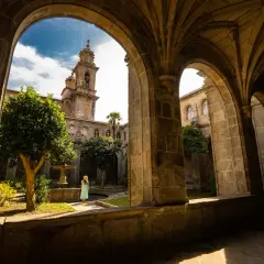 Una mujer contempla el patio interior del monasterio de Poio, con su fuente y campanario al fondo.