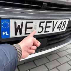 Palec wskazujący na hologram na tablicy rejestracyjnej. Uniknij kary za nieprzerejestrowanie pojazdu, dbając o aktualne dokumenty.