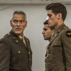 George Clooney w mundurze, obok dwóch młodych żołnierzy. Jeden z nich ma opatrunek na nosie. Scena jak z paragrafu 22.