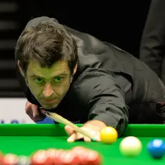 Ronnie O'Sullivan w akcji, skupiony na grze w snookera. Jego sportowa pasja widoczna w każdym ruchu.