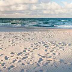 Piasek na plaży, ślady stóp i fale morza. Idealne miejsce, gdzie nad morze.