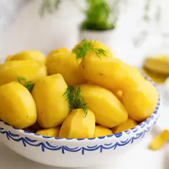 En skål med nykokta, gula potatisar, garnerade med dill. Perfekt för att koka potatis till middagen.