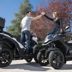 Pareja chocando las manos junto a sus Qooder QV3, listos para una aventura.