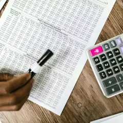 Tabela z danymi finansowymi, kalkulator i ręka analizująca układ rodzajowy kosztów.