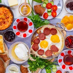 Reichhaltiges türkisches Frühstück: Eier mit Sucuk, Käse, Oliven, Honig und Gebäck. Welches Lebensmittel hat die meisten Kalorien? Wahrscheinlich das Gebäck oder die Wurst.