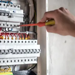 Elektryk przy skrzynce z bezpiecznikami. Dowiedz się, jak obliczyć, ile prądu zużyje urządzenie, sprawdzając jego moc.