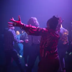 Publiken njuter av en konsert på kulturhuset. En kvinna i röd mönstrad tröja dansar med armarna uppsträckta.