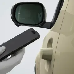 Dłoń w białej rękawiczce zbliża smartfon do klamki samochodu Hyundai. Bluelink umożliwia bezkluczykowe otwieranie.