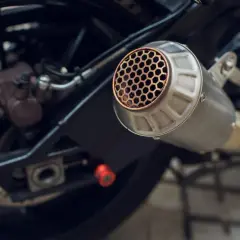 Scarico moto con griglia a nido d'ape, un **db killer fai da te** per un suono più discreto. Si intravede la ruota posteriore e il freno.