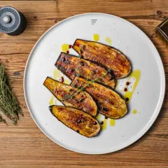 Gegrillte Auberginenscheiben als Antipasti, beträufelt mit Olivenöl und Balsamico, garniert mit Thymian.