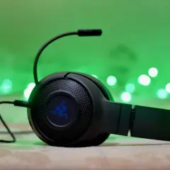 Słuchawki gamingowe Razer z mikrofonem, podłączone przez combo jack, na tle zielonych światełek.