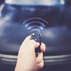 Dłoń trzyma kluczyk z pilotem, z którego wychodzą fale sygnału. Czy to sposób, jak wyłączyć alarm w samochodzie na stałe?