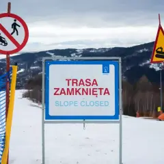 Na stoku narciarskim widoczne są wskaźniki kolejowe: zakaz saneczkarstwa, tablica "Trasa zamknięta" oraz znak ostrzegawczy z ratrakiem.