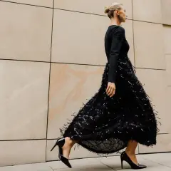 Elegancka kobieta w czarnej sukience z cekinami i piórkami, czarne szpilki. Idealne dodatki do czarnej cekinowej sukienki.