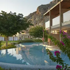 En vacker pool reflekterar bergen vid aegean park rhodos. Blommor och grönska omger hotellet.