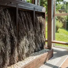 Wnętrze z tężniami solankowymi, gdzie gałązki tworzą naturalną ścianę, a podłogę zdobią kamyki.