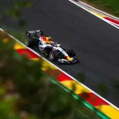 Liam Lawson compite en un coche de Fórmula 1 con los colores de Red Bull, acelerando en una curva con las marcas rojas y amarillas de la pista.