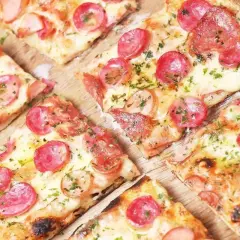 Kawałki pizzy z kiełbasą i serem, posypane ziołami. Idealne ciasto na pizzę dla każdego smakosza.