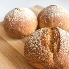 Pane dorato e fragrante, appena sfornato nella friggitrice ad aria, cosparso di farina su un tagliere di legno.