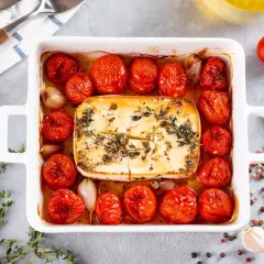 Feta in friggitrice ad aria, circondata da pomodorini arrostiti, aglio e erbe aromatiche. Un piatto semplice e gustoso.