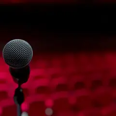 Mikrofon na statywie na tle czerwonych foteli. Chcesz wiedzieć, jak lepiej śpiewać? To miejsce dla Ciebie.