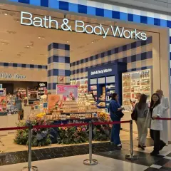 Sklep Bath & Body Works z promocjami, wystawą kwiatów i klientami.