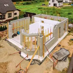 Budowa domu styropianowego w toku. Widać fundamenty, ściany z bloczków i elementy szalunku.