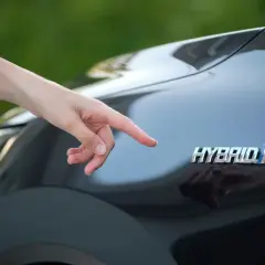 Dito il logo "Hybrid" su una Toyota Yaris. Si pensa al costo del bollo per un'auto ibrida.